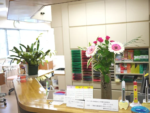 花と案内表示が置かれた清水歯科医院の受付カウンター